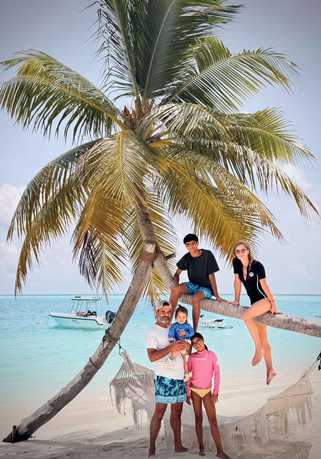The Chablani and Norris family under a palm tree on a Maldives beach